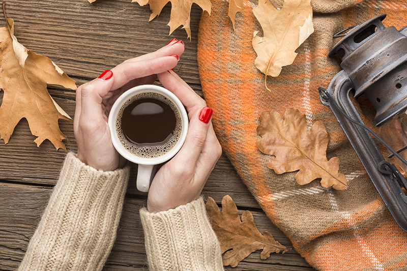 top-view-person-holding-coffee-cup-with-autumn-leaves-lantern